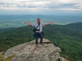 asiatico Grasso uomo In piedi su roccioso scogliera e il trekking su khao luang montagna nel ramkhamhaeng nazionale parco, sukhothai Provincia Tailandia foto