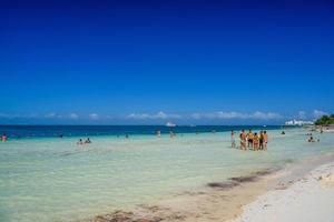 gruppo di persone in piedi nel il acqua spiaggia su un' soleggiato giorno nel Cancun, yukatan, Messico foto