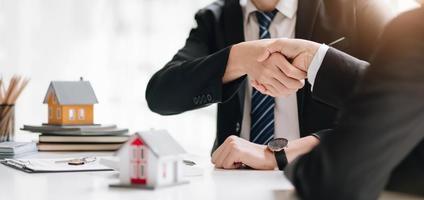 agente immobiliare e cliente che si stringono la mano dopo aver firmato un contratto immobiliare, mutuo per la casa e concetto di assicurazione foto