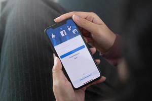 donna che tiene un iphone x con servizio internet sociale facebook sullo schermo.