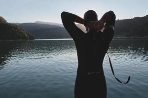 atleta di triathlon che inizia l'allenamento di nuoto sul lago foto