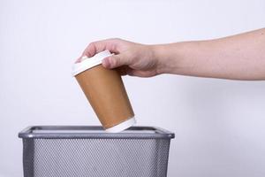 riciclaggio, separato rifiuto collezione, mano lanci un' tazza di caffè in il spazzatura Potere. foto