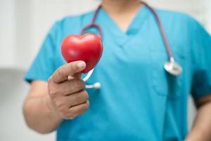 medico che tiene un cuore rosso nel reparto ospedaliero, concetto medico sano e forte. foto