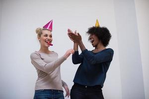 sorridente donne nel festa caps soffiaggio per fischietti foto