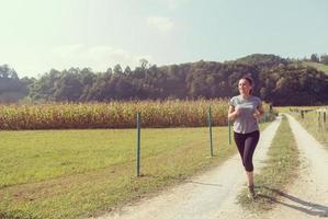 donna che fa jogging lungo una strada di campagna foto