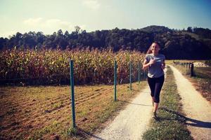 donna che fa jogging lungo una strada di campagna foto