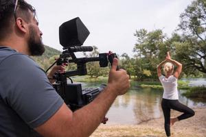 giovane operatore video registrazione mentre donna fare yoga esercizio foto