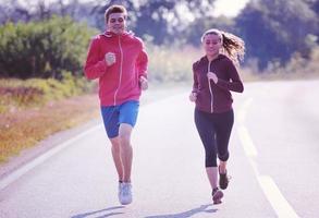 giovane coppia fare jogging lungo una strada di campagna foto