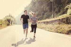 giovane coppia fare jogging lungo una strada di campagna foto