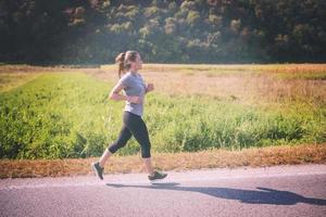 donna che fa jogging lungo una strada di campagna foto