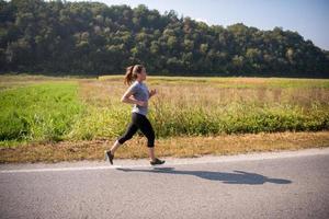 donna che fa jogging lungo una strada di campagna foto