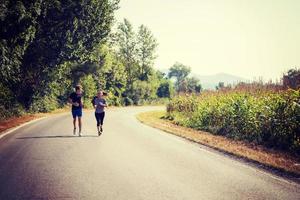 giovane coppia fare jogging lungo una strada di campagna foto