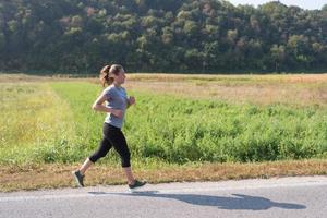 donna che fa jogging lungo una strada di campagna foto