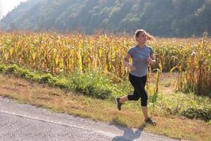 donna che fa jogging lungo una strada di campagna foto