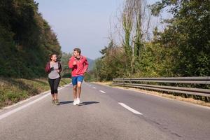 giovane coppia fare jogging lungo una strada di campagna foto