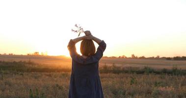 giovane testa Rossa donna nel bellissimo boho vestito rilassante nel il campo durante nebbioso tramonto, femmina all'aperto con mazzo nel mani foto