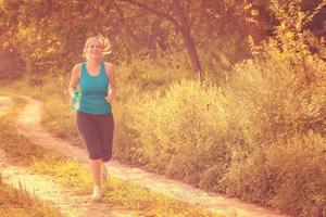 donna che fa jogging lungo una strada di campagna foto