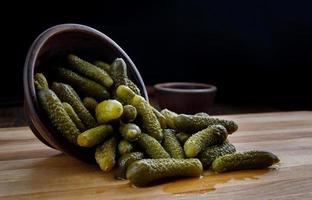 succoso croccante sottaceto cetrioli siamo versato a partire dal un' argilla tazza su un' di legno taglio tavola. salato cetrioli. foto