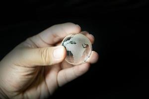 la sfera di vetro del pianeta terra e l'immagine della mano. foto