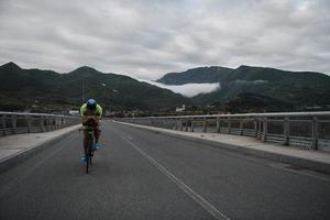 atleta di triathlon in sella a una bicicletta durante l'allenamento mattutino foto