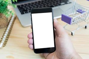 mani Tenere vuoto schermo di smartphone su legna scrivania opera. foto