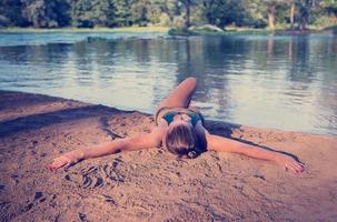 ragazza nel un' verde bikini rilassante su il Riva del fiume foto