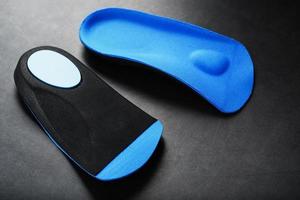 ortopedico solette per correzione di il blu colore di il piede su un' nero sfondo. foto