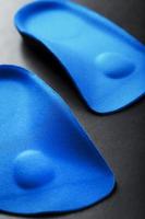 ortopedico solette per correzione di il blu colore di il piede su un' nero sfondo. foto