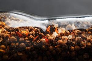 un' miscela di grani di pepe stagionatura e sale nel un' trasparente mulino avvicinamento foto
