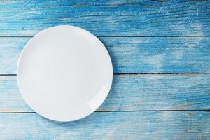 un vuoto il giro bianca piatto su un' blu di legno tavolo. foto