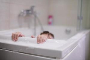 poco ragazza nel bagno giocando con sapone schiuma foto