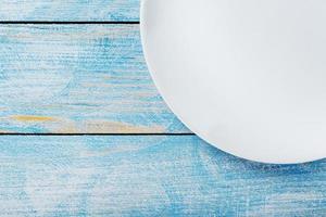 un vuoto il giro bianca piatto su un' blu di legno tavolo. foto
