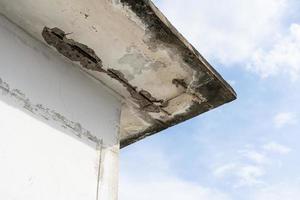 tetto del soffitto danneggiato dall'acqua in una vecchia casa. danni causati dall'acqua all'interno dell'edificio. soffitto casa rotto. crepa di cemento del soffitto ed esposto il telaio della barra d'acciaio arrugginito. foto