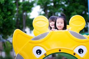 Due ragazze scalato su il tubo e sat e rideva. bambini siamo felice, sorridente, dolce e luminosa. asiatico bambini anziano 3 - 5 anni. foto