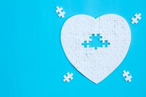 a forma di cuore bianco di pezzi di puzzle su sfondo blu. concetti di risoluzione dei problemi, successo aziendale, lavoro di squadra, gioco di puzzle di squadra incompleto, banner di texture con spazio di copia per il testo foto