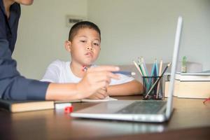 giovane alunno distanza apprendimento virtuale distanza in linea classe su video chiamata virtuale lezione con madre, studiando a casa utilizzando il computer portatile computer. genitore o precettore insegnamento bambino ragazzo con a distanza formazione scolastica foto