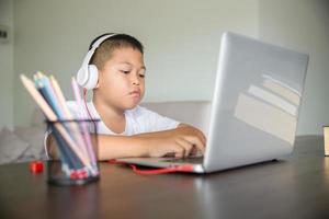 giovane alunno distanza apprendimento virtuale distanza in linea classe su video chiamata virtuale lezione, tecnologia studiando a casa utilizzando il computer portatile computer. genitore o precettore insegnamento bambino ragazzo con a distanza formazione scolastica. foto