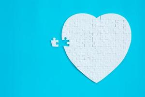 a forma di cuore bianco di pezzi di puzzle su sfondo blu. concetti di risoluzione dei problemi, successo aziendale, lavoro di squadra, gioco di puzzle di squadra incompleto, banner di texture con spazio di copia per il testo foto