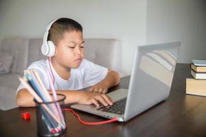 giovane alunno distanza apprendimento virtuale distanza in linea classe su video chiamata virtuale lezione, tecnologia studiando a casa utilizzando il computer portatile computer. genitore o precettore insegnamento bambino ragazzo con a distanza formazione scolastica. foto