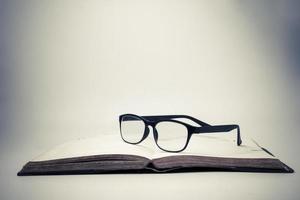 occhiali su un Aperto libro con Vintage ▾ sfondo. foto