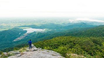 giovane uomo godendo un' valle Visualizza a partire dal superiore di un' montagna. foto