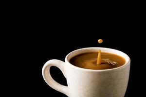 un' tazza di caffè con un' far cadere su nero sfondo. foto