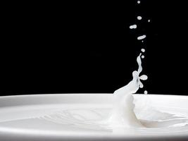 spruzzo di latte a partire dal un' tazza su nero sfondo. foto