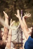 gruppo di giovane amici giocando spiaggia pallavolo foto