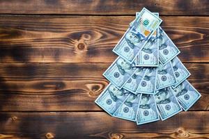 Natale albero fatto di 100 dollaro fatture su di legno sfondo con copyspace. Natale arredamento su tema di finanza, risparmio, ricchezza, spese nel nuovo anno. in modo piatto. pila di 100, investimenti, attività commerciale foto