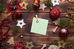 Natale piatto posare di rosso palloncini e di legno stelle e mollette su un' buio sfondo con un' piazza foglio per Appunti nel il centro. nuovo anni telaio, spazio per testo. natale giocattoli, perline, pino rami foto