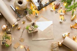 busta con congratulazioni per natale e capodanno in materiali ecologici carta kraft, rami di abete vivo, pigne, spago. tag mock up, arredamento naturale, fatto a mano. lettera per babbo natale. in modo piatto foto