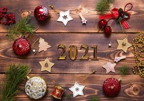 Natale piatto posare con nuovo anno 2021 simbolo di oro numeri nel il centro. vacanza atmosfera, di legno stelle, giocattoli, perline, rosso palle, abete rosso rami su un' buio sfondo. spazio per testo foto