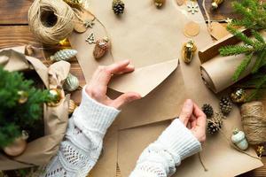 busta con congratulazioni per natale e capodanno in materiali ecologici carta kraft, rami di abete vivo, pigne, spago. tag mock up, arredamento naturale, fatto a mano. lettera per babbo natale. in modo piatto foto