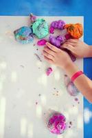 mani del bambino che giocano con l'argilla colorata foto